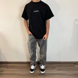 Remera negra de algodón con estampado de un tiburón en color naranja y tipografía en blanco.