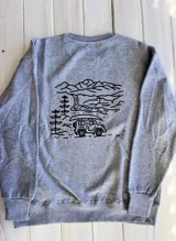 Buzo gris con cuello redondo y puños acanalados. Estampado en la espalda con diseño de montañas, árboles, río y camioneta.
