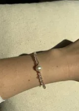 Pulsera elástica con cuentas facetadas de cristal rosa, detalles de acero dorado y una perla barroca de río.
