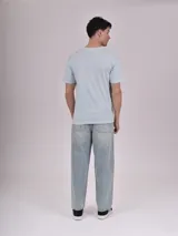 Remera celeste de manga corta con estampa rectangular con imagen del mar y texto en la parte superior.