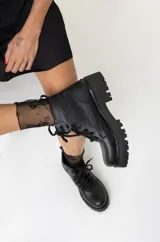 Borcegos de cuero negro con cordones, suela track y caña baja.