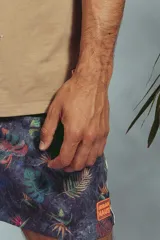 Short de baño con estampado de hojas en tonos grises y celestes, con cordón ajustable en la cintura y detalle de franja lateral con rayas rojas, blancas y negras.