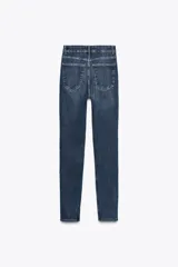 Jeans skinny de tiro alto en denim azul oscuro, con cinco bolsillos y cierre frontal con cremallera y botón metálico.