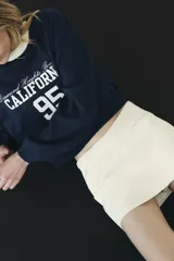 Falda pantalón color crema de tiro bajo con cintura asimétrica, bolsillos delanteros de vivo y cierre lateral con cremallera oculta.