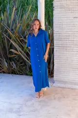 Vestido camisero de muselina color negro, de largo midi, con cuello clásico, manga corta y cierre frontal con botones.