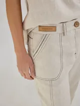 Pantalón largo color beige de lino, con bolsillos delanteros y traseros, cierre con botón y presillas para cinturón.