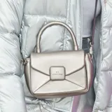 Cartera bandolera color peltre, con diseño acolchado en símil cuero y costuras a tono. Tiene acceso con solapa, correa regulable y asa fija. Cuenta con un bolsillo interno con cierre y un bolsillo externo abierto.