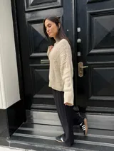 Sweater color crema de punto trenzado, con cuello alto y mangas largas.