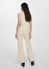 Top color beige de tejido de punto con cuello alto y sin mangas.