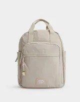 Mochila color beige de tela deportiva con doble bolsillo frontal con cierre, correas regulables, cierre superior y tag de goma.