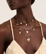 Maxi collar de capas con tres cadenas de hilo encerado negro y dijes de corazones dorados de diferentes estilos.