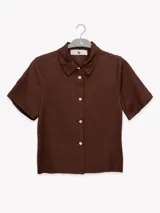 Camisa marrón de lino con cuello clásico, manga corta y cierre frontal con botones blancos.