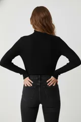 Polera de manga larga color beige claro, de tejido acanalado y cuello alto, de calce ajustado al cuerpo.