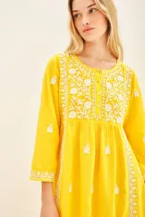 Vestido amarillo largo hasta los tobillos, con cartera de botones símil nacar en el delantero y bordado a contratono a lo largo de toda la prenda.
