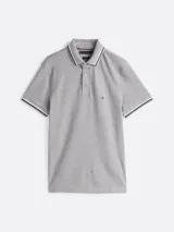 Chomba gris de algodón elástico con cuello y mangas ribeteadas en blanco y negro. Tiene cartera de tres botones, logo de Tommy Hilfiger bordado en el pecho y corte slim.