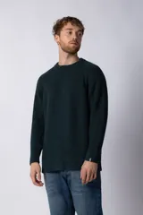 Sweater marrón de punto con cuello redondo y mangas largas raglán. Tejido grueso con textura acanalada. Corte holgado.