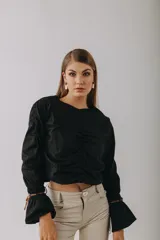 Camisa negra de algodón con mangas largas abullonadas y detalle de tientos de cuero en los puños.