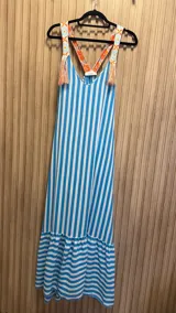 Vestido largo de algodón con estampado de rayas verticales celestes y blancas. Breteles con detalle de bordado floral y borlas.