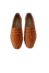 Mocasín de gamuza color terracota con detalle de tachas metálicas.
