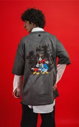 Remera oversize de algodón premium, color gris oscuro con efecto gastado (acid wash), con cuello redondo y manga corta. Presenta un pequeño estampado de Mickey Mouse en el pecho.