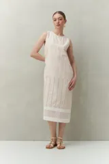 Vestido largo color beige, sin mangas, confeccionado en algodón con calados verticales y bordado tipo ojo de perdiz.