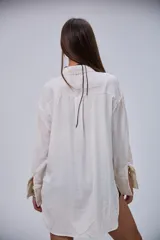 Camisa de manga larga color beige, con cuello clásico y botones frontales.