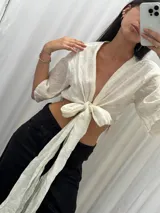 Top de lino color crudo con mangas amplias y lazo versátil para atar al frente o cruzarlo y ajustarlo atrás.