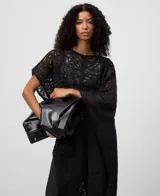 Capa de punto cardado en color negro con diseño asimétrico y bordado calado. Presenta escote redondeado y aberturas laterales. Confeccionada en una mezcla de mohair y lyocell que aporta suavidad y ligereza.