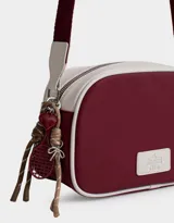 Bandolera de cuerina azul marino y beige con correa regulable azul y charm lateral decorativo. Tiene cierre superior y tag frontal con logo "The Brunch Club".