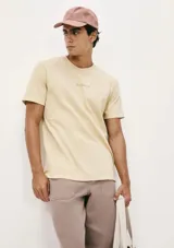 Remera color beige de manga corta con cuello redondo y estampado pequeño en el pecho.