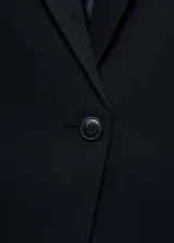 Blazer entallado color negro con cuello de pico con solapa y muesca, manga larga con puños abotonados, dos bolsillos de ribete en la parte delantera, un bolsillo de ribete en el pecho, cierre de botones en la parte delantera, abertura posterior en el bajo y forro interior.