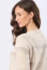 Buzo tejido de cuello redondo, color beige con estampado abstracto en tonos rosados y grises. Tiene mangas largas con puños acanalados y un pequeño parche de cuero sintético en el dobladillo.