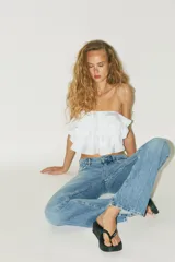 Top bandeau color crema con escote recto, hombros descubiertos y detalle de volantes en capas.