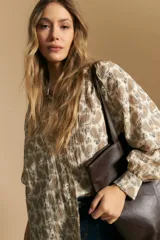 Camisa de manga larga con cuello mao y estampado paisley en tonos beige, marrón y azul sobre fondo claro. Presenta un calce holgado y puños ajustados.