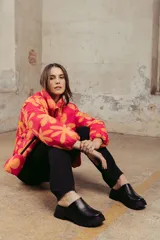 Campera puffer estampada con flores color naranja sobre fondo fucsia, de corte corto y cuello alto.