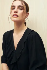 Blusa negra con mangas 3/4 y escote en V con volados.