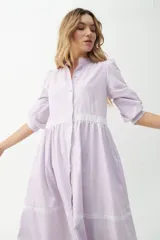 Vestido camisero midi color beige a rayas verticales, con cuello mao, mangas 3/4 abullonadas y festones de algodón en el cuerpo. Cierre frontal con botones.