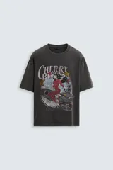 Camiseta negra de corte holgado con cuello redondo y mangas cortas. Estampado frontal con una ilustración de una mujer en un cohete y la leyenda "Cherry Pilot Blush Delight".