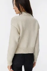 Sweater tejido color crudo con cuello redondo y mangas largas. Presenta detalles de ochos en el frente y está confeccionado artesanalmente en Uruguay.
