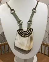 Collar con cadena dorada, tiras de gamuza verde claro y dije de guampa con apliques metálicos dorados.