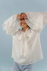 Blusa color blanco con lazo en el cuello y mangas largas con volados.