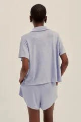 Conjunto de pijama de tela toalla color lavanda, compuesto por una camisa de manga corta con botones y un short con cintura elastizada y cordón ajustable.