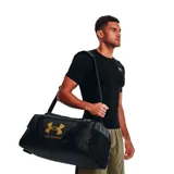 Bolso deportivo Under Armour modelo Big Undeniable 5.0, color negro con logo dorado. Cuenta con asas de mano y correa ajustable para el hombro.