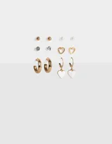 Set de aros dorados con diferentes diseños: aros tipo argolla, aros con forma de corazón, aros con perlas, aros con strass y aros tipo botón.