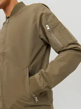 Campera bomber verde militar de Jack & Jones, con cuello de béisbol, cierre con cremallera, bolsillos frontales con cremallera y bolsillo en la manga.