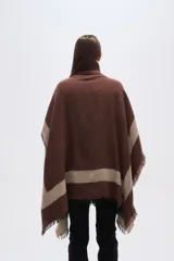 Poncho de tejido grueso, color negro y gris, con diseño de franjas diagonales y cuello alto con cierre. Presenta terminaciones con flecos.