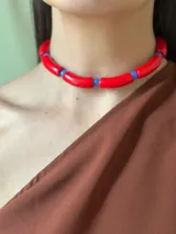Gargantilla con cuentas de tubo acrílicas rojas y cristales checos azules. Se cierra con cadena de acero quirúrgico y ganchito para regular el largo.