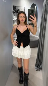 Minifalda blanca de tiro bajo con volados y cordón ajustable en la cintura.