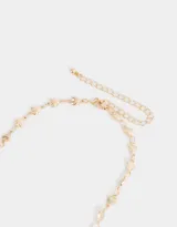 Collar corto dorado con cadena de eslabones y dije de strass con forma de corazón.