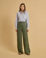 Pantalón de lino verde con rayas verticales negras y blancas, de tiro alto, corte palazzo y bolsillos laterales.
